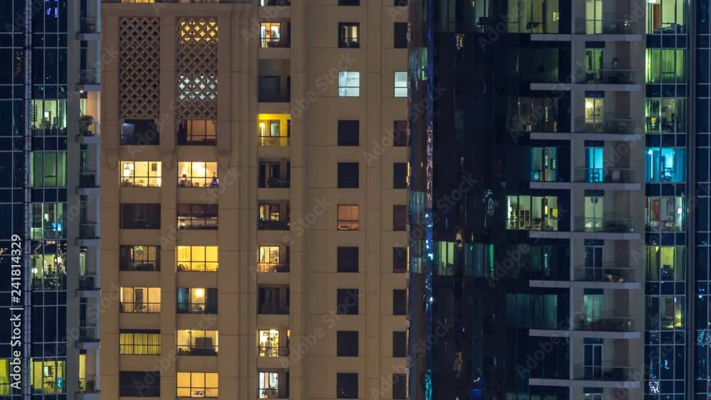 Glowing windows in multistory modern glass and metal residential building light up at night timelapse. Glowing windows in multistory modern glass and metal residential building light up at night timelapse.