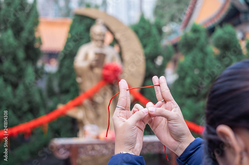 Young woman ties red rope and pray at Yue Lao (God of marriage) in Wong Tai Sin Temple, is well known for love and marriage prayers answered. landmark and popular for tourist attractions in Hong Kong photo