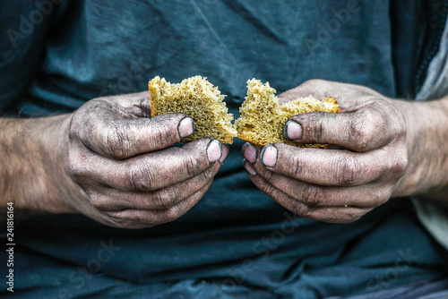 Dirty hands homeless poor man with piece of bread in modern capitalism society