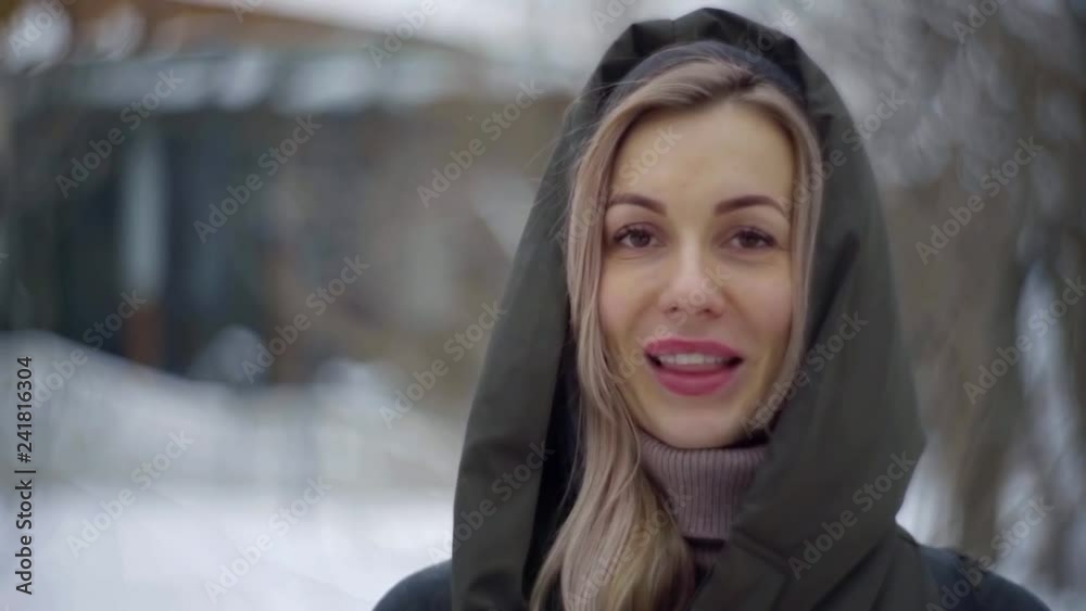 adult blonde woman with dark eyes and braces on teeth is smiling broadly outdoors in winter day adult blonde woman with dark eyes and braces on teeth is smiling broadly outdoors in winter day