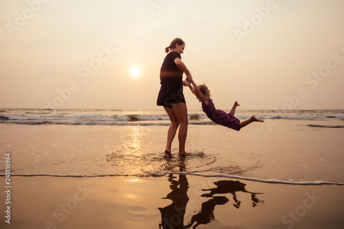happy family at the beach. mother hugging child daughter and fly tourism with children
