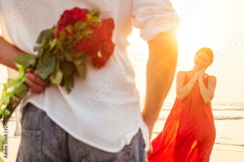 Valokuvatapetti happy beautiful woman in red dress receiving a gift from a man by sea sunset
