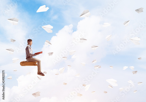 Handsome man student reading book and paper planes flying around © adam121