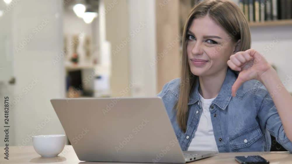 Thumbs Down by Creative Girl Looking at Camera at Work Thumbs Down by Creative Girl Looking at Camera at Work