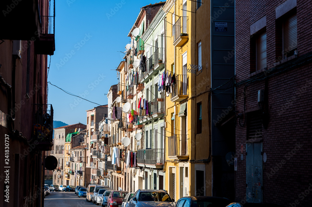 view of street with colorful houses in small catalan spanish medieval town during sunny spring day and clear blue sky