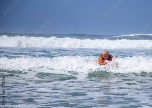 Granny having so much fun on a body board in the surf.