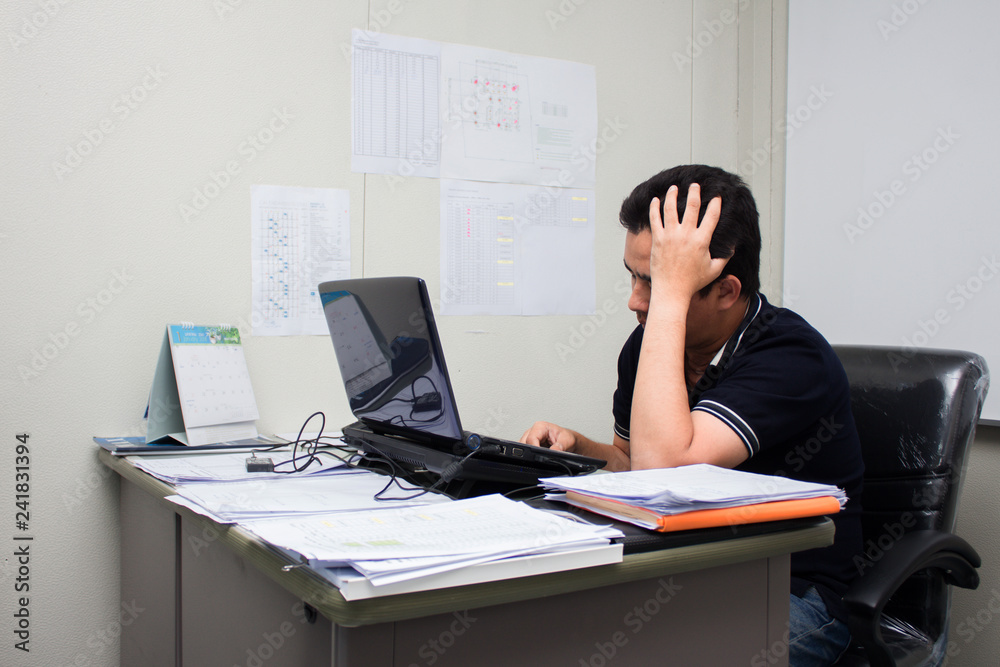 A man working in the office him serious and headache with burnout A man working in the office him serious and headache with burnout