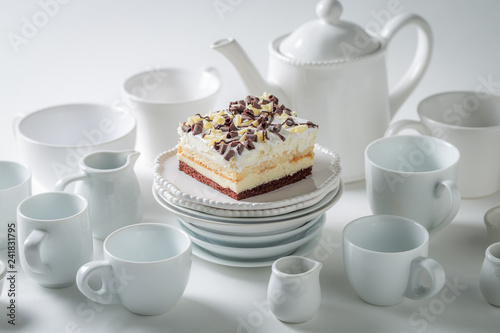 White cake with mousse, chocolate and porcelain on white background