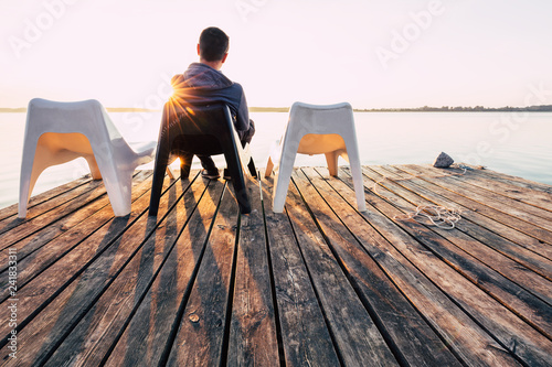Obraz na płótnie Men is relaxing and meditation on chair at footbridge on lake. Concept of waiting for summer. w salonie