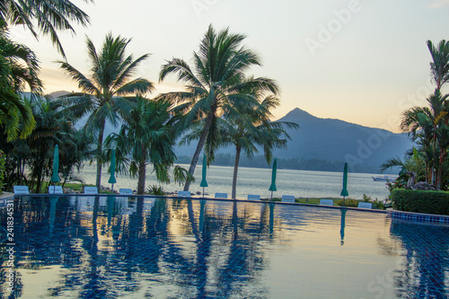 Beautiful sunrise over the pool and palm trees © marinadatsenko