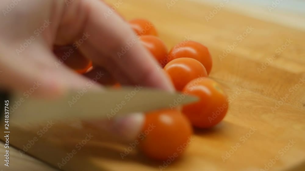 Close up shot hands of women using kitchen knife slide cut fresh tomato on wooden cutting board preparing for cooking