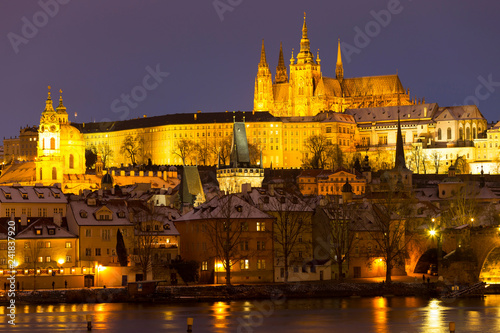 Night colorful snowy Christmas Prague Lesser Town with gothic Castle and Charles Bridge, Czech republic