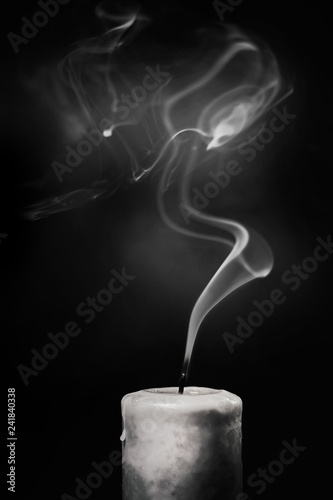 Extinct white candle with smoke on a black background