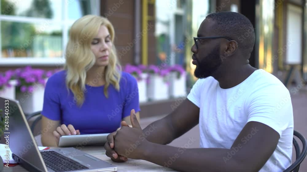 Customer and employee discussing details of project using tablet and laptop Customer and employee discussing details of project using tablet and laptop