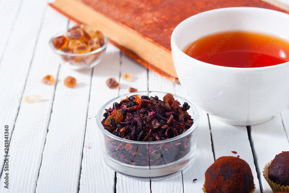 herbal tea, brown sugar, chocolate truffles and an old book on white wooden table herbal tea, brown sugar, chocolate truffles and an old book on white wooden table
