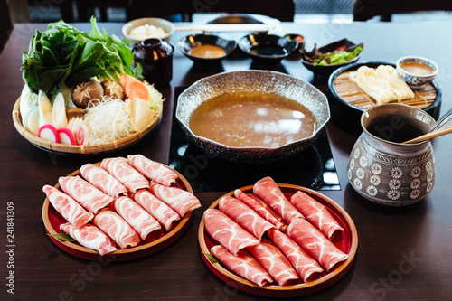 Premium Rare Slices Kurobuta (Black Pig) pork with high-marbled texture on circle wooden plates served with vegetable set for Sukiyaki and Shabu.