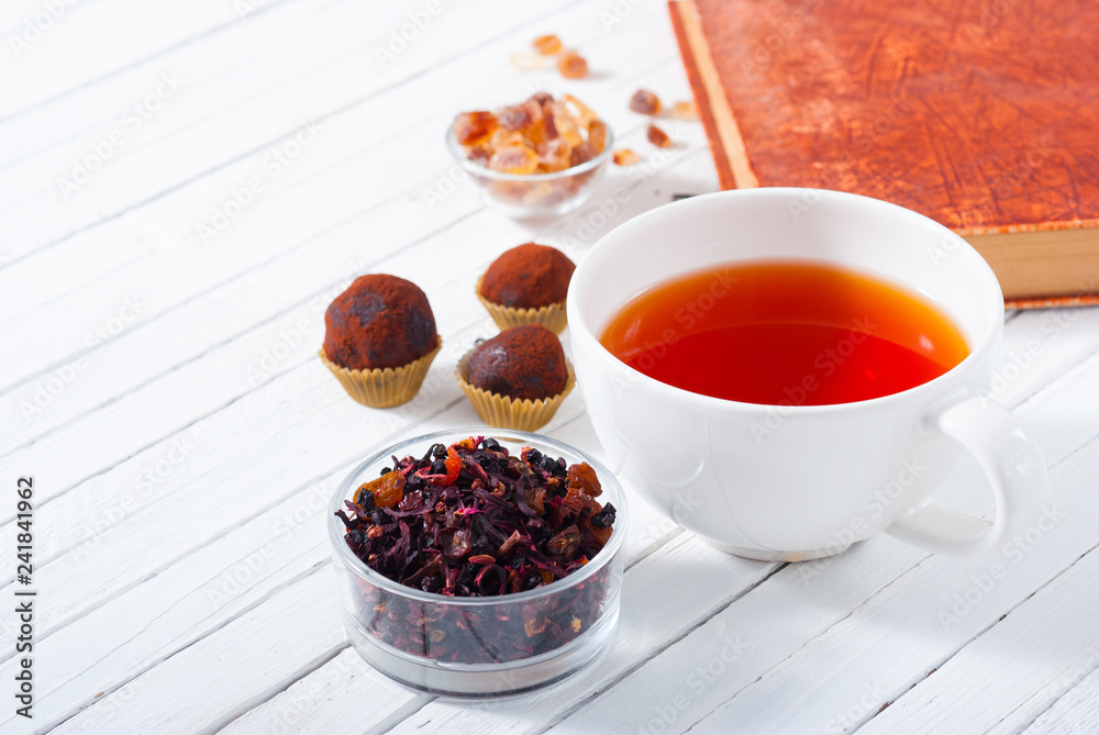 herbal tea, brown sugar, chocolate truffles and an old book on white wooden table herbal tea, brown sugar, chocolate truffles and an old book on white wooden table