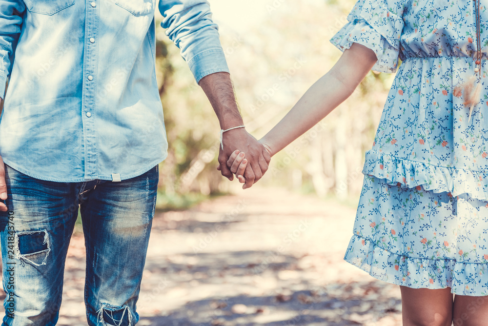 Young couple holding hands and walking through pathway on the street. Filtered image. Young couple holding hands and walking through pathway on the street. Filtered image.