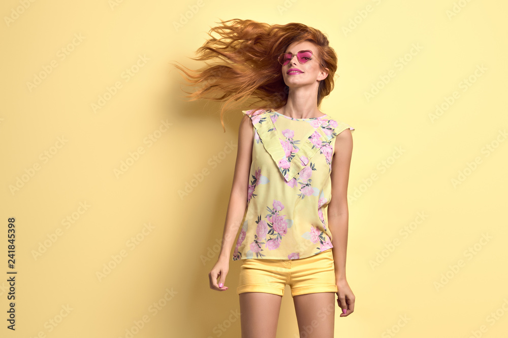 Girl jumping fooling around in studio. Young beautiful happy woman having fun smiling dance in Fashion Stylish outfit, makeup. Cheerful redhead model on yellow Girl jumping fooling around in studio. Young beautiful happy woman having fun smiling dance in Fashion Stylish outfit, makeup. Cheerful redhead model on yellow