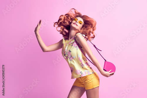 Girl jumping fooling around in studio. Young beautiful pretty woman having fun laughing dance in Fashion Stylish outfit, makeup. Cheerful redhead model on purple