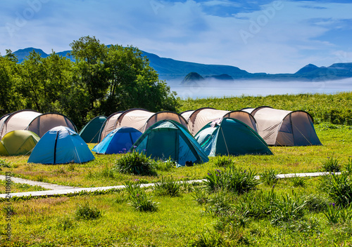 Fototapeta Naklejka Na Ścianę i Meble -  Tourists camped in the woods on the shore of the lake on the hillside.