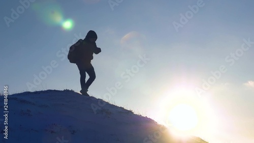 Tourist with backpack travels on snow-capped mountains. climber gently descends from snowy mountain, slides down in rays of bright sun.
