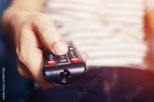 Close up young man using television remote control is sitting on a sofa. on or off tv. 
