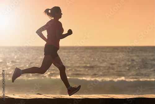 Woman running on beach in morning sunrise, fitness workout sport