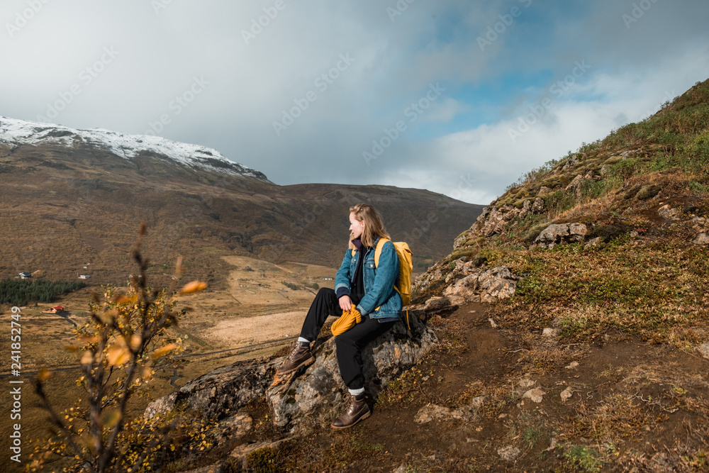 woman sitting on rocky cliff and looking at amazing Nordic landscape, Iceland. Travel and nature. 