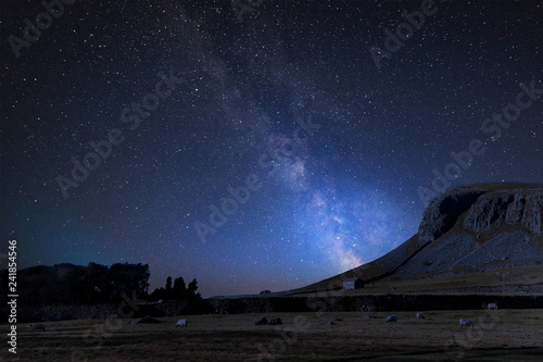 Vibrant Milky Way composite image over landscape of Norber Ridge and stone barn in Yorkshire Dales National Park photo