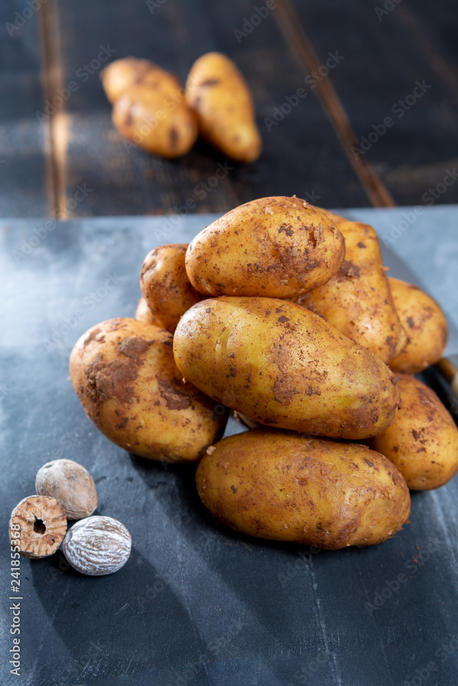 New harvest potatoes not washed with soil on table with nutmeg New harvest potatoes not washed with soil on table with nutmeg