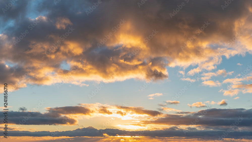 Beautiful colorful vibrant golden hour sunset skyscape with cloud formation and setting sun