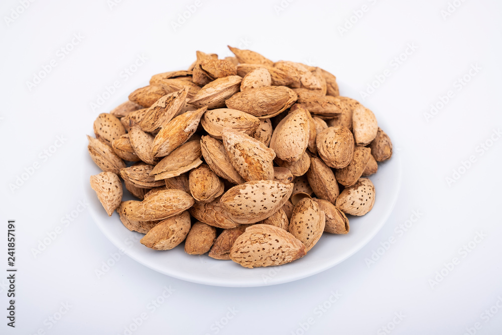 Almond nuts in shells and they are in white porcelain bowl Almond nuts in shells and they are in white porcelain bowl