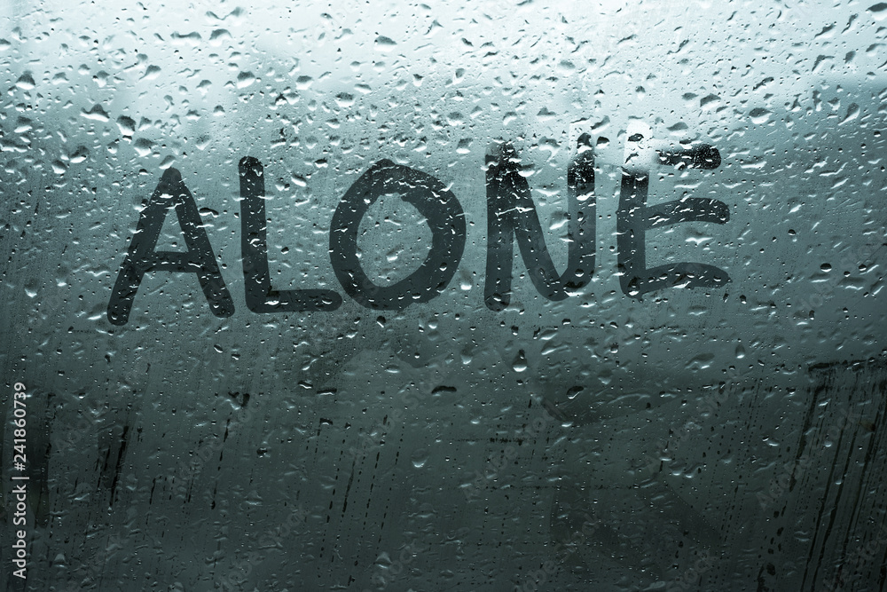 Handwritten word alone on fog up glass window with rain drops in cold dark tones, illustrates