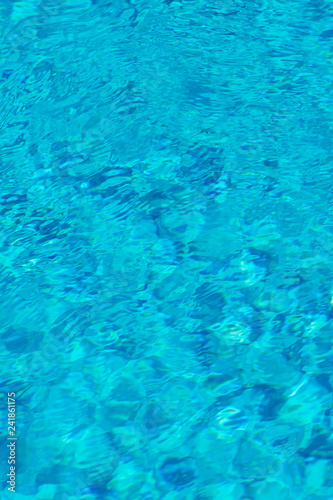 Blue water in swimming pool background. Ripple Water in swimming pool with sun reflection. Blue swimming pool rippled water detail. vertical photo.