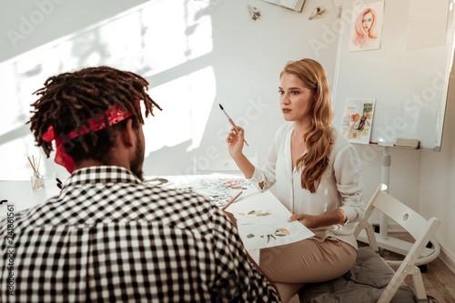 Artist holding painting brush while teaching her student photo