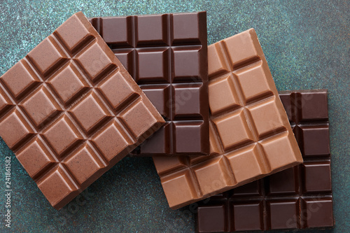 Various milk and dark square shape chocolate bars on wooden background, top view