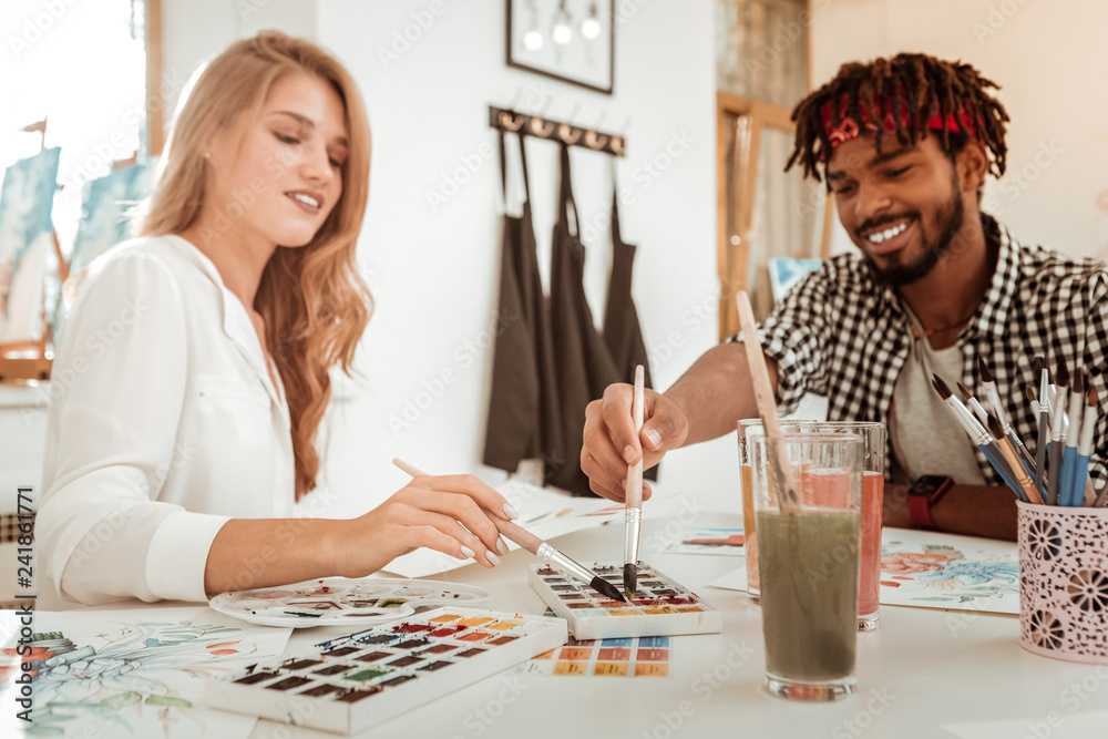 Fototapeta premium Loving handsome boyfriend joining his appealing girlfriend drawing