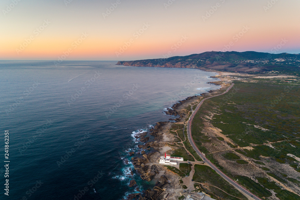 Aerial view of the Guincho area, with the Cabo Raso Lighthouse, the scenic road along the coast and the Roca Cape (Cabo da Roca) on the background; 