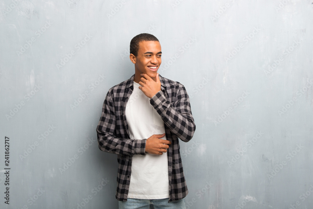 Young african american man with checkered shirt looking to the side with the hand on the chin