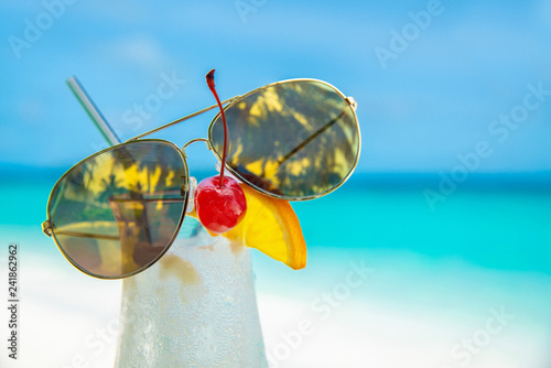 sunglass on cocunut cocktail and sea background on clear sky day photo