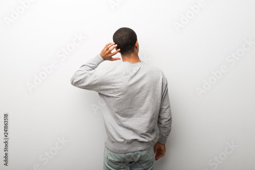 African american man on white wall background on back position looking back while scratching head