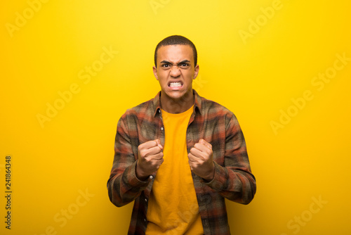 Young african american man on vibrant yellow background frustrated by a bad situation © luismolinero