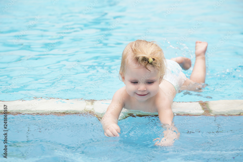 Portrait of a happy baby girl in the swimming pool 