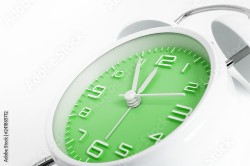 Table alarm clock with time 5 to 12 with green clock face, 11.55 AM PM, on white background photo