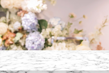 abstract blur beautiful flowers and floral background in beauty shop with white marble texture perspective counter for promote and show and advertise product on display