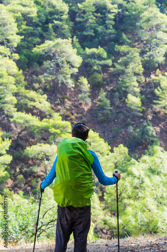 Peaceful person in harmony with nature. Anonymous man with a hiking bag and trekking poles in the mountains.