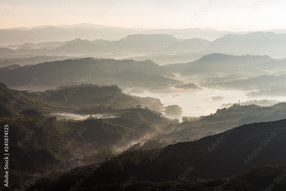 View over mountain from a mountain peak. Panorama view over mountains and lake. Misty morning just after sunrise. Nature landscape.