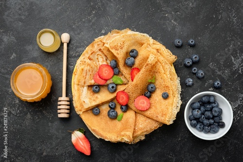 Crepes or blini with berries and honey. Maslenitsa food. Table top view