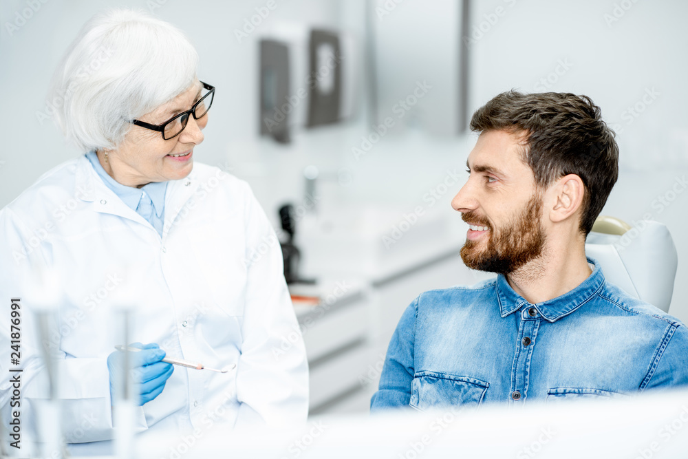 Obraz premium Handsome man during the dental consultation with elderly woman dentist in the dental office
